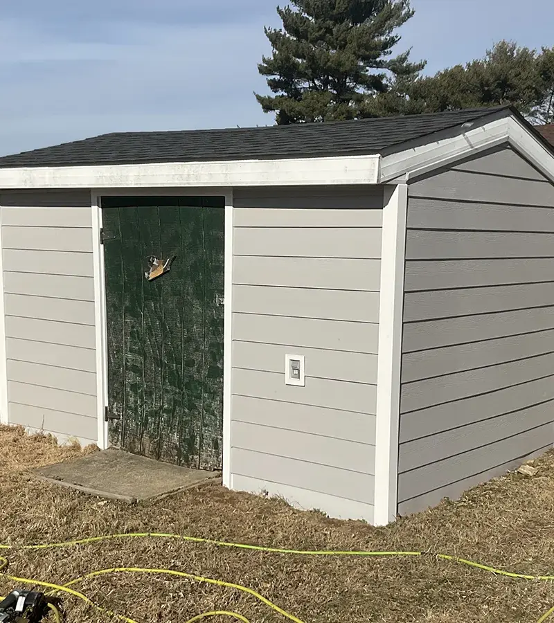 A detached shed with a green standing seam metal roof.