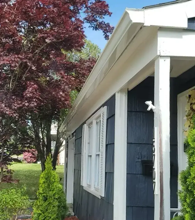 A detached shed with a green standing seam metal roof.