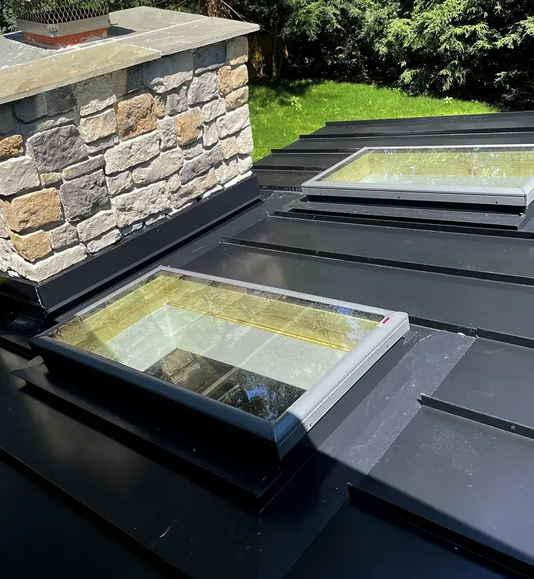 Black standing seam metal roof with 2 skylights and custom fabricated metal flashing.