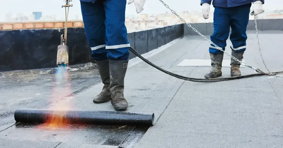 Two roofing contractors install torch-down roofing