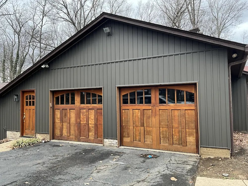 dark color board and batten siding with wood stained garage doors. 